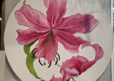 A round plate featuring a vibrant pink flower painting.