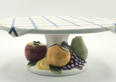 Decorative ceramic pedestal bowl with fruit illustrations.