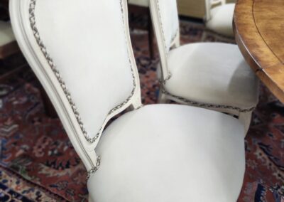 Elegant cream upholstered chairs with nailhead trim around the edges.