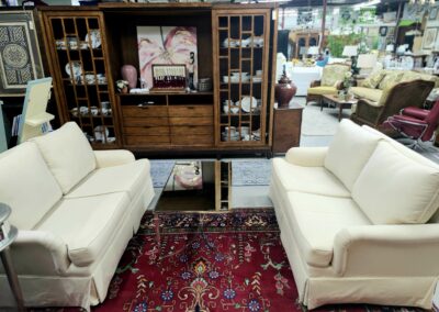 Elegant living room setup with cream sofas, wooden cabinet, and red patterned rug.