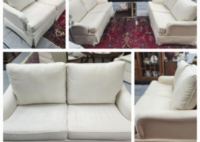 White cushioned sofa set with wooden legs on a red patterned rug.