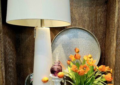 Cozy indoor scene with a white lamp and vibrant orange tulips.