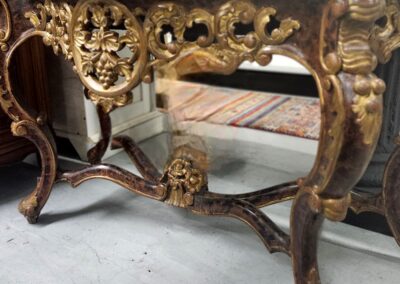 Ornate antique wooden table with gold accents and intricate carvings.