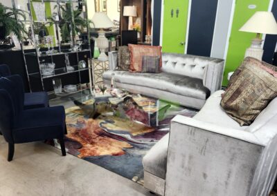 Modern living room with gray sofas, glass coffee table, and colorful rug.