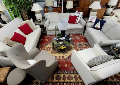 Cozy living room with white sofas and red accent pillows around a glass coffee table.