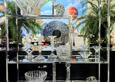Elegant glassware displayed on tiered shelves with a decorative backdrop.