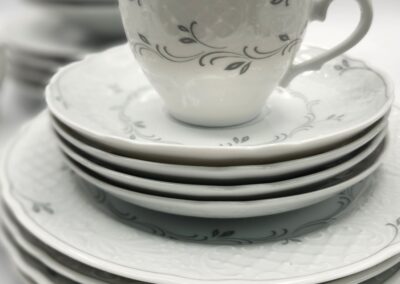 Elegant white porcelain tea cup and matching plates with delicate floral patterns.