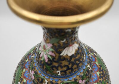 A close-up of an ornate vase with a gold rim and intricate floral patterns.
