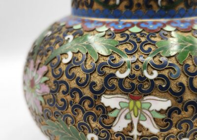 Close-up of a colorful, ornate cloisonné vase with intricate floral and swirl patterns.