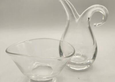 Two elegant clear glass vessels with unique shapes on a neutral background.