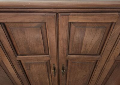 Wooden cabinet with paneled doors and metal handles.