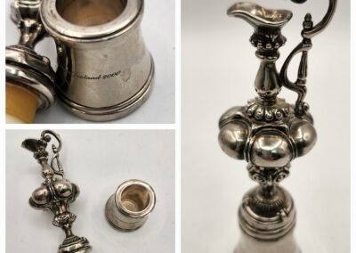 Antique silver pitcher with intricate design and wooden handle.