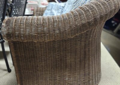A woven wicker chair with a curved backrest in a store setting.