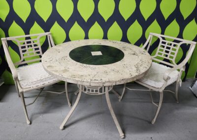 Round stone table with a glass center and white metal chairs.