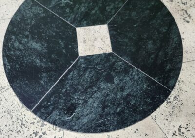 Round black stone with a square cutout in the center on a speckled surface.