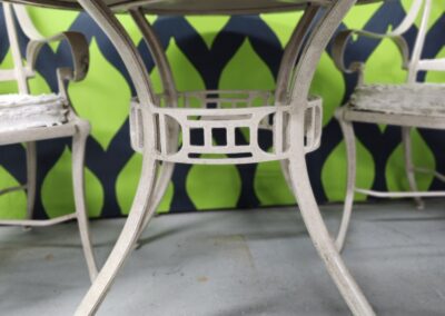 White metal round table with a patterned green and blue background.