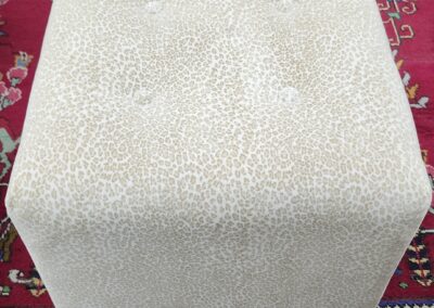 White textured cube ottoman on a patterned rug.
