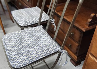 Two metal chairs with patterned cushions in a room with wooden furniture.