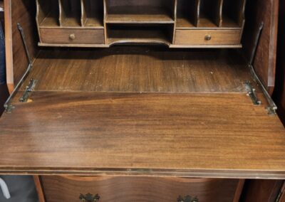 Open vintage wooden secretary desk with compartments and drawers.