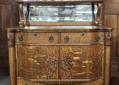 Ornate wooden dresser with intricate carvings and a mirror on top.