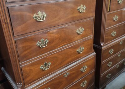 Two wooden dressers with brass handles in a storage setting.