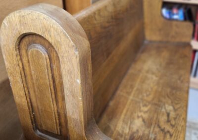 Close-up of a wooden bench with detailed armrest design.