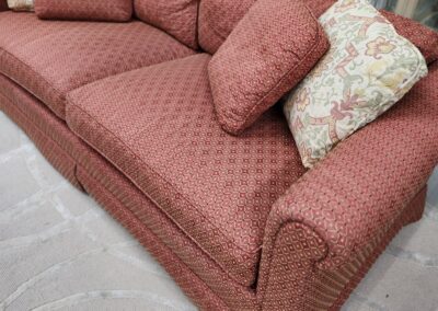 A red patterned sofa with three cushions, one floral.