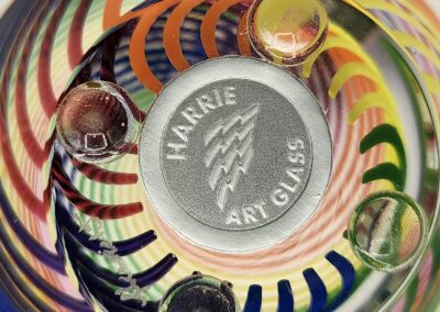 Colorful swirled glass bowl with four distinct glass knobs and a central logo.