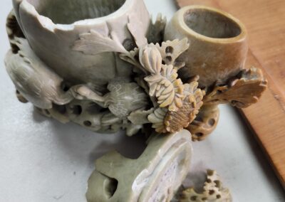 Intricately carved wooden pipe with floral details and dice nearby.