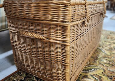 Woven wicker basket with handles on a patterned carpet.