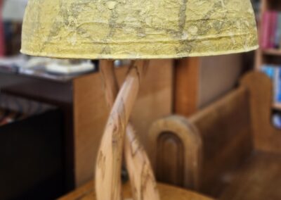 Artistic wooden lamp with a globe-shaped shade on a wooden table.