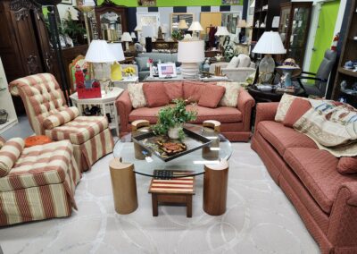 A cozy living room setup with two red sofas, striped armchairs, and various decorative items.