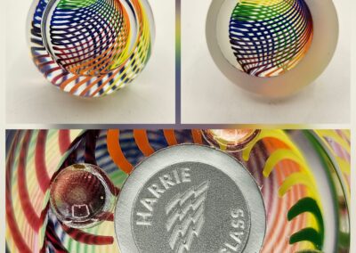 Colorful glass paperweights with intricate swirling patterns and a branded base.