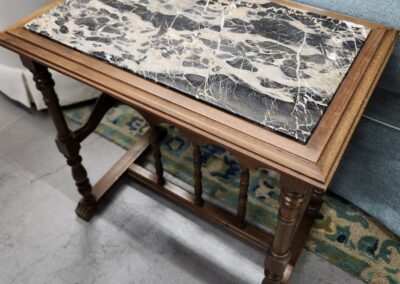 Wooden table with intricate marble top and decorative legs.