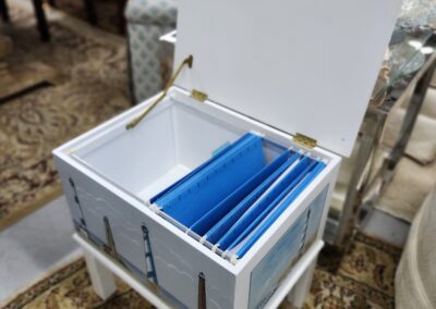White wooden chest filled with blue plastic folders, placed indoors.