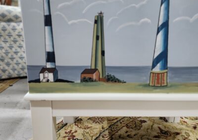 Miniature models of three distinct lighthouses displayed on a white table.