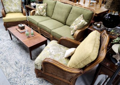 Cozy green sofa and wicker chair with cushions in a living room setup.