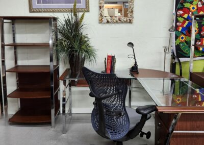 A tidy office corner with a mesh chair, wooden shelves, and a glass desk.
