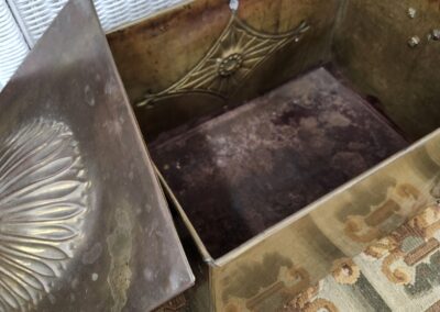 An open antique brass chest with decorative etched patterns.