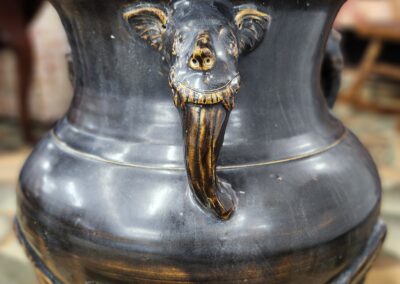 Black ceramic vase with a goat face design and a beard.