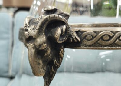 Decorative glass table with ram head metal embellishment.