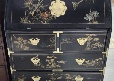Elegant black lacquered cabinet with gold floral designs and multiple drawers.