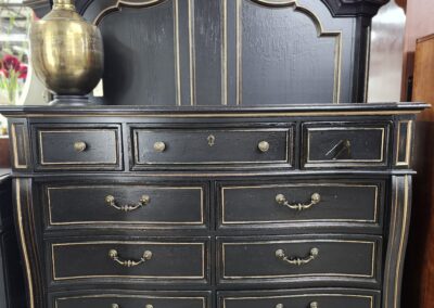 Black vintage dresser with multiple drawers and brass handles.