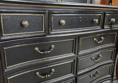 Elegant black dresser with curved drawers and brass handles.