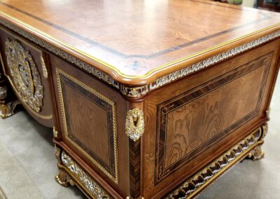 Ornate wooden desk with intricate carvings and gold accents.