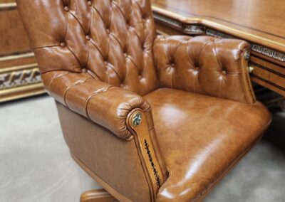 A classic brown leather tufted office chair with wooden accents.