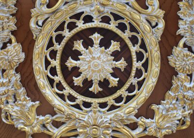 Ornate gold and wood carved circular design with floral motifs.
