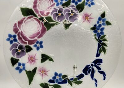 Decorative plate with a floral wreath design in pink, purple, and blue.
