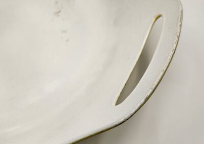 Close-up of a white ceramic dish handle with a smooth finish.