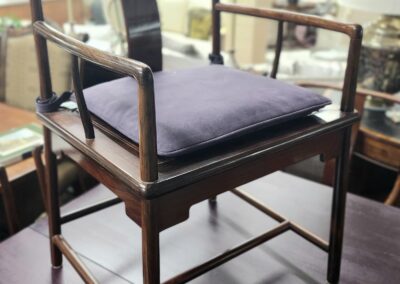 A wooden chair with a soft cushion in a well-lit room.